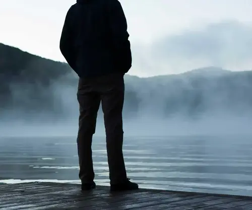 Człowiek na skraju plaży jeziora i góry